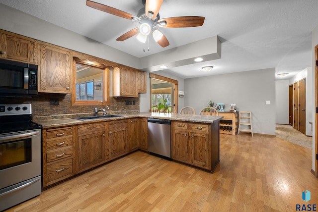 4108 E 23rd St, Sioux Falls, SD 57103 - kitchen featuring appliances with stainless steel finishes, a sink, light wood-style floors, a peninsula, and backsplash