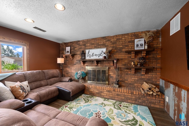 4108 E 23rd St, Sioux Falls, SD 57103 - living room with a brick fireplace, a textured ceiling, brick wall, wood finished floors, and visible vents