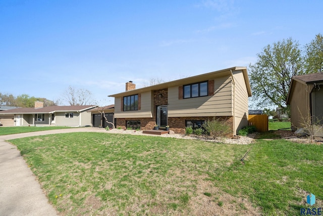 4108 E 23rd St, Sioux Falls, SD 57103 - bi-level home with concrete driveway, brick siding, a chimney, and a front lawn