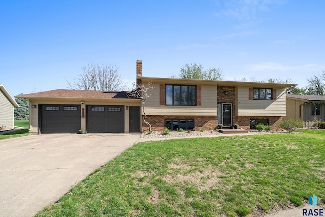 4108 E 23rd St, Sioux Falls, SD 57103 - split foyer home with a front yard, a chimney, brick siding, concrete driveway, and an attached garage