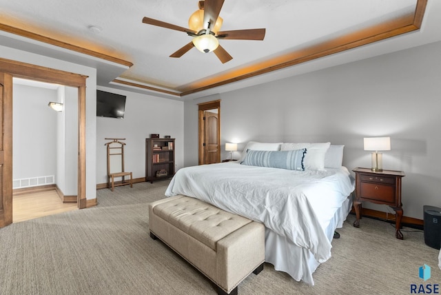 carpeted bedroom with a ceiling fan, baseboards, visible vents, and a raised ceiling