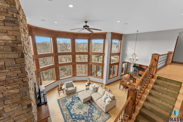living area featuring stairs, recessed lighting, wood finished floors, and ceiling fan with notable chandelier