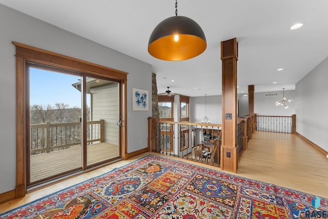interior space featuring a notable chandelier, baseboards, an upstairs landing, wood finished floors, and visible vents