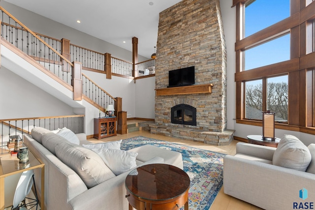 living area featuring a fireplace, baseboards, stairway, and a towering ceiling