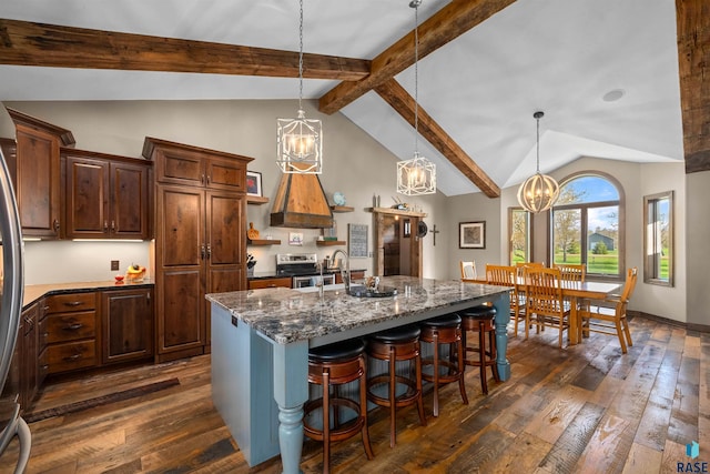 kitchen featuring a breakfast bar area, an inviting chandelier, a center island with sink, and dark wood-type flooring