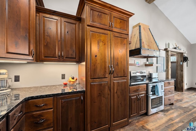 kitchen featuring lofted ceiling, custom exhaust hood, dark wood-style floors, dark stone countertops, and double oven range