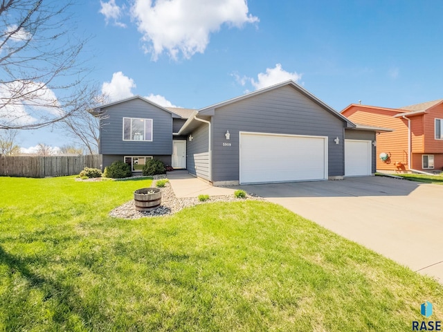 split level home with a garage, a front lawn, fence, and driveway