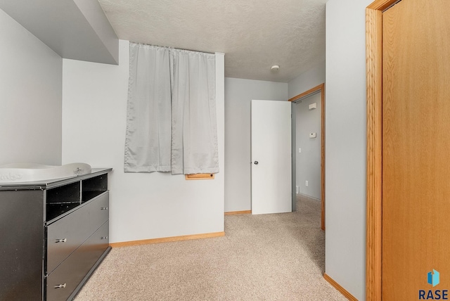 unfurnished bedroom with a textured ceiling, baseboards, and carpet