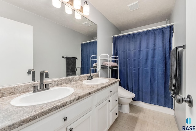bathroom with double vanity, a sink, visible vents, and toilet