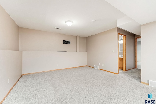 basement featuring baseboards, light carpet, and visible vents