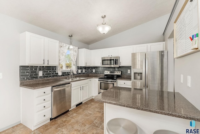 kitchen featuring white cabinets, appliances with stainless steel finishes, a sink, decorative backsplash, and lofted ceiling