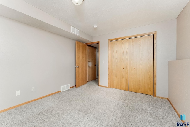 unfurnished bedroom with visible vents, carpet flooring, and a closet