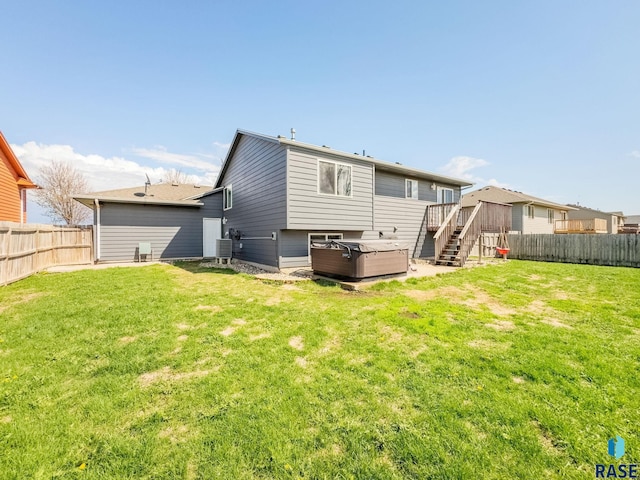 back of house featuring stairway, a lawn, and a fenced backyard