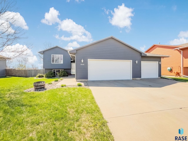 view of front of property with fence, a garage, driveway, and a front lawn