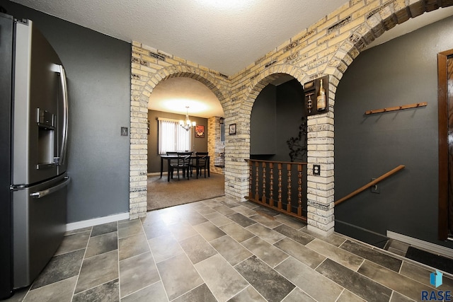 interior space with decorative columns, baseboards, an inviting chandelier, and a textured ceiling