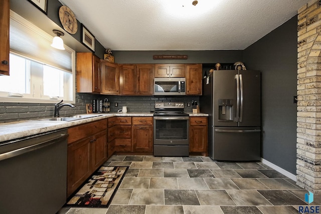 kitchen with light countertops, appliances with stainless steel finishes, brown cabinetry, and a sink