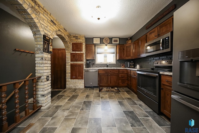 kitchen featuring a textured ceiling, appliances with stainless steel finishes, a sink, and tasteful backsplash