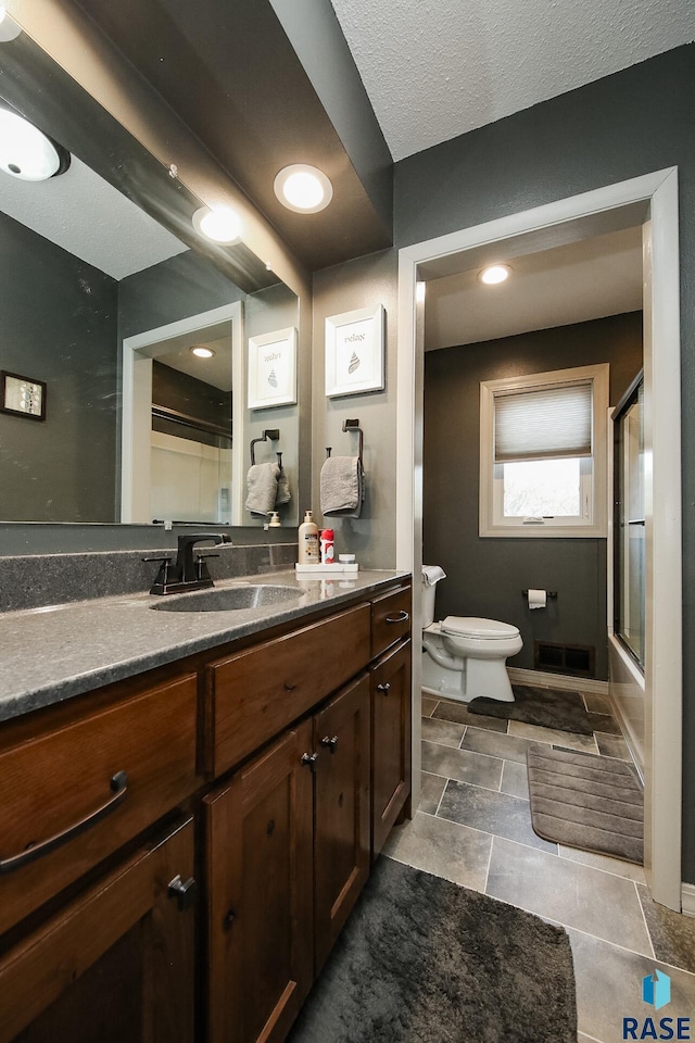 bathroom featuring vanity, toilet, baseboards, visible vents, and bath / shower combo with glass door