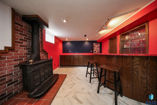 bar featuring a sink, marble finish floor, a wood stove, and indoor bar