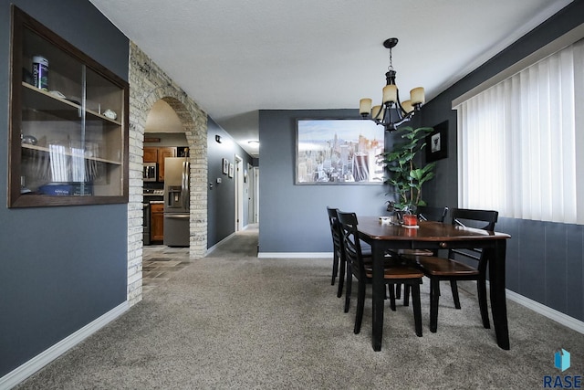 carpeted dining space featuring arched walkways, baseboards, and a notable chandelier