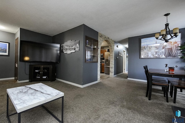 living area with an inviting chandelier, carpet floors, baseboards, a textured ceiling, and arched walkways
