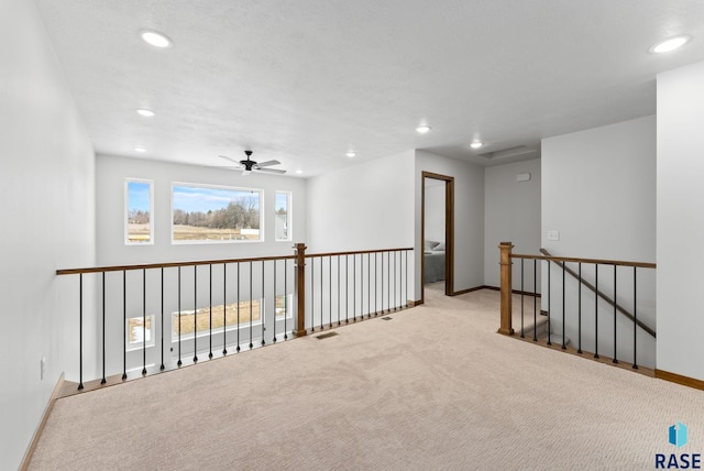 hall with recessed lighting, baseboards, and an upstairs landing