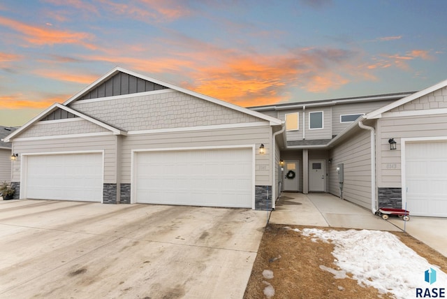 view of property featuring concrete driveway, an attached garage, and stone siding
