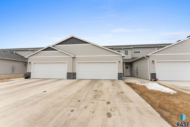 multi unit property featuring concrete driveway, stone siding, and a garage