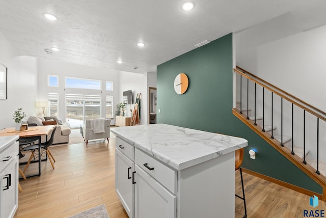 kitchen featuring a kitchen island, light wood-style flooring, open floor plan, recessed lighting, and white cabinetry