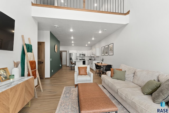 living room featuring recessed lighting, baseboards, and light wood-type flooring