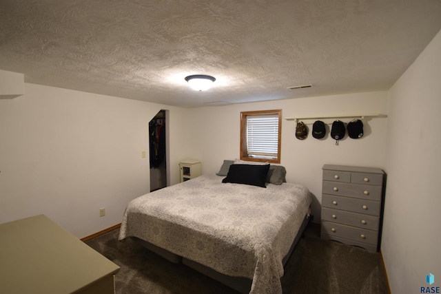 bedroom with baseboards, dark colored carpet, a textured ceiling, and visible vents