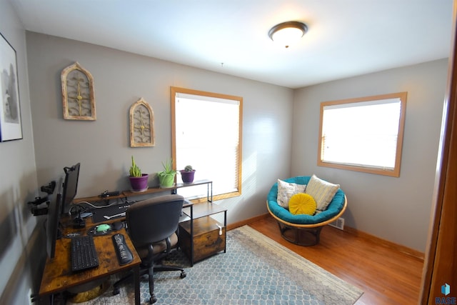 office space with plenty of natural light, baseboards, wood finished floors, and visible vents