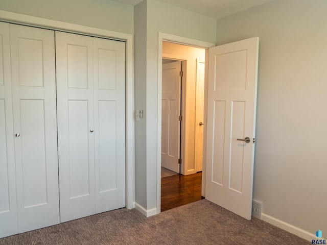 unfurnished bedroom featuring carpet floors, baseboards, a closet, and visible vents