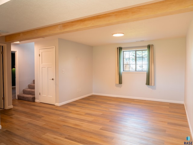 unfurnished room with baseboards, stairs, and light wood-style flooring
