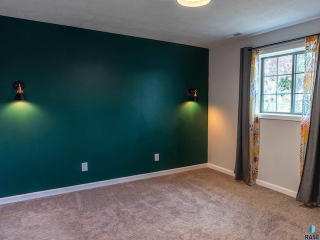 carpeted spare room featuring baseboards and visible vents