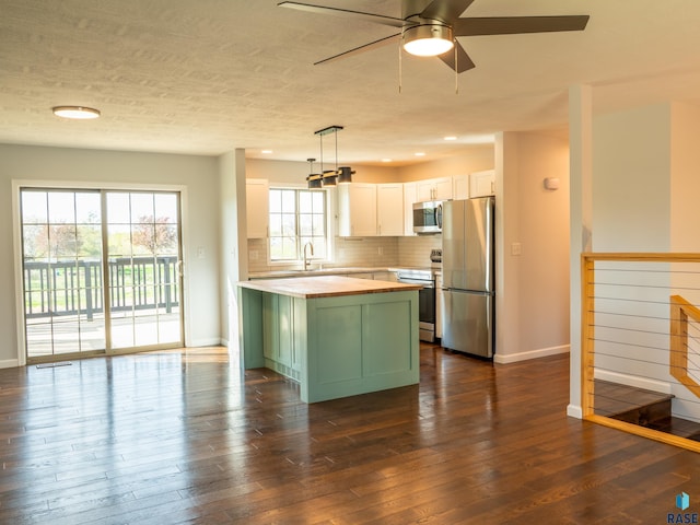 kitchen with appliances with stainless steel finishes, baseboards, butcher block counters, and green cabinets
