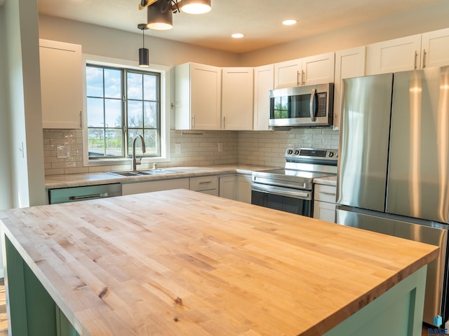 kitchen featuring a sink, appliances with stainless steel finishes, butcher block countertops, and white cabinetry