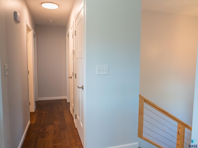hallway featuring baseboards and dark wood finished floors