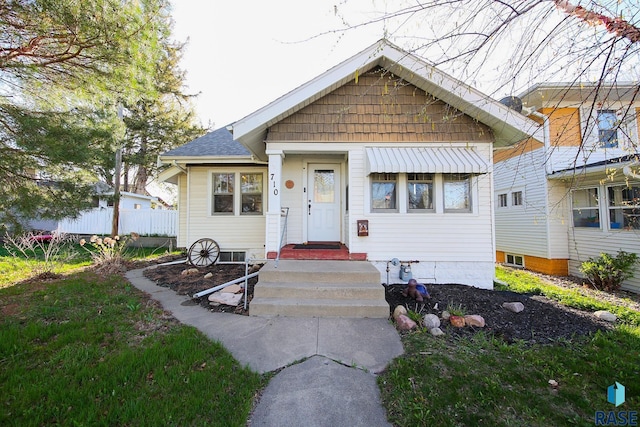 bungalow-style home with fence and roof with shingles