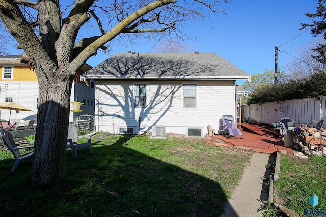 back of property featuring fence, a wooden deck, a lawn, and central air condition unit