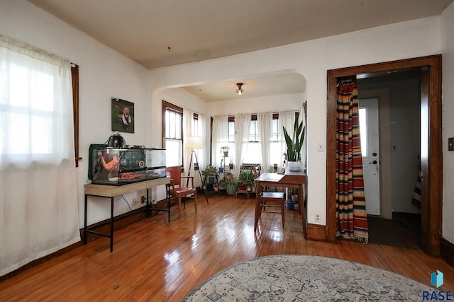 sitting room featuring arched walkways and wood finished floors