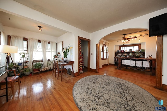 foyer entrance featuring baseboards, arched walkways, a ceiling fan, and wood finished floors