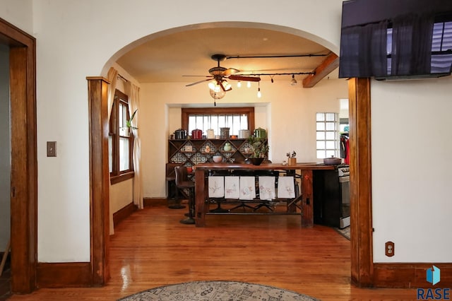 dining area featuring arched walkways, ceiling fan, and wood finished floors