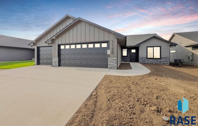 1125 E Wayne Pl, Tea, SD 57064 - view of front of house featuring board and batten siding, stone siding, cooling unit, an attached garage, and concrete driveway