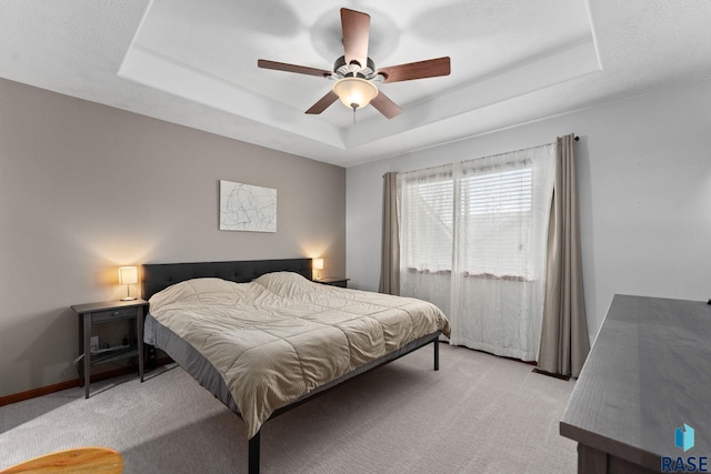 bedroom with baseboards, carpet flooring, ceiling fan, and a tray ceiling
