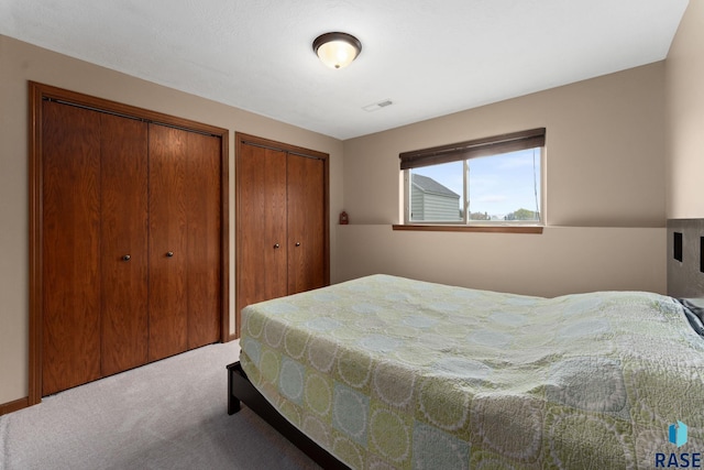 carpeted bedroom with visible vents and multiple closets