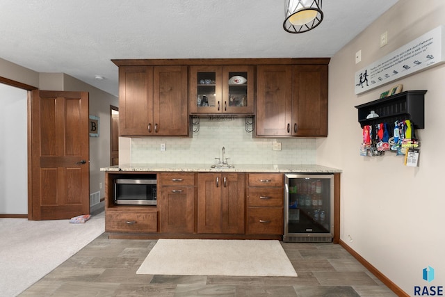 bar featuring baseboards, tasteful backsplash, stainless steel microwave, and beverage cooler