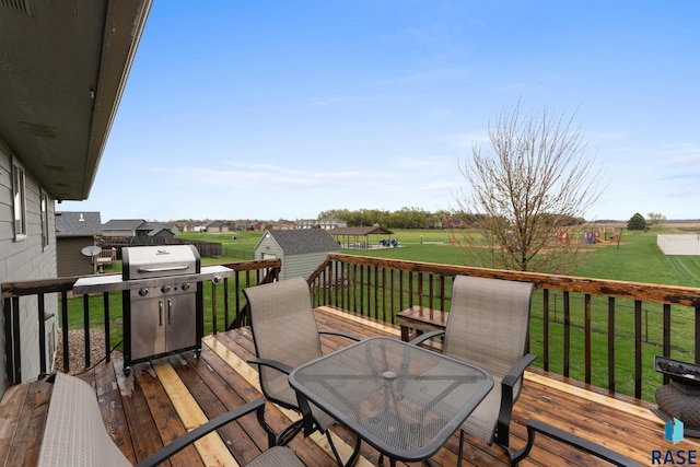 wooden terrace with outdoor dining space, a storage shed, grilling area, an outdoor structure, and a yard