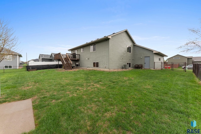 rear view of house with a lawn, a wooden deck, central AC unit, stairway, and a fenced backyard