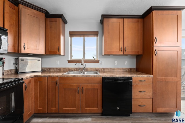kitchen with a sink, wood finished floors, black appliances, and brown cabinets